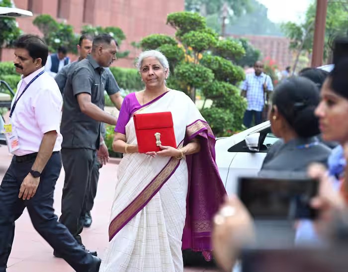बैंगनी बॉर्डर वाली सफेद साड़ी में लाल बैग हाथ में थामें बजट पेश करने पहुंची वित्त मंत्री निर्मला सीतारमण